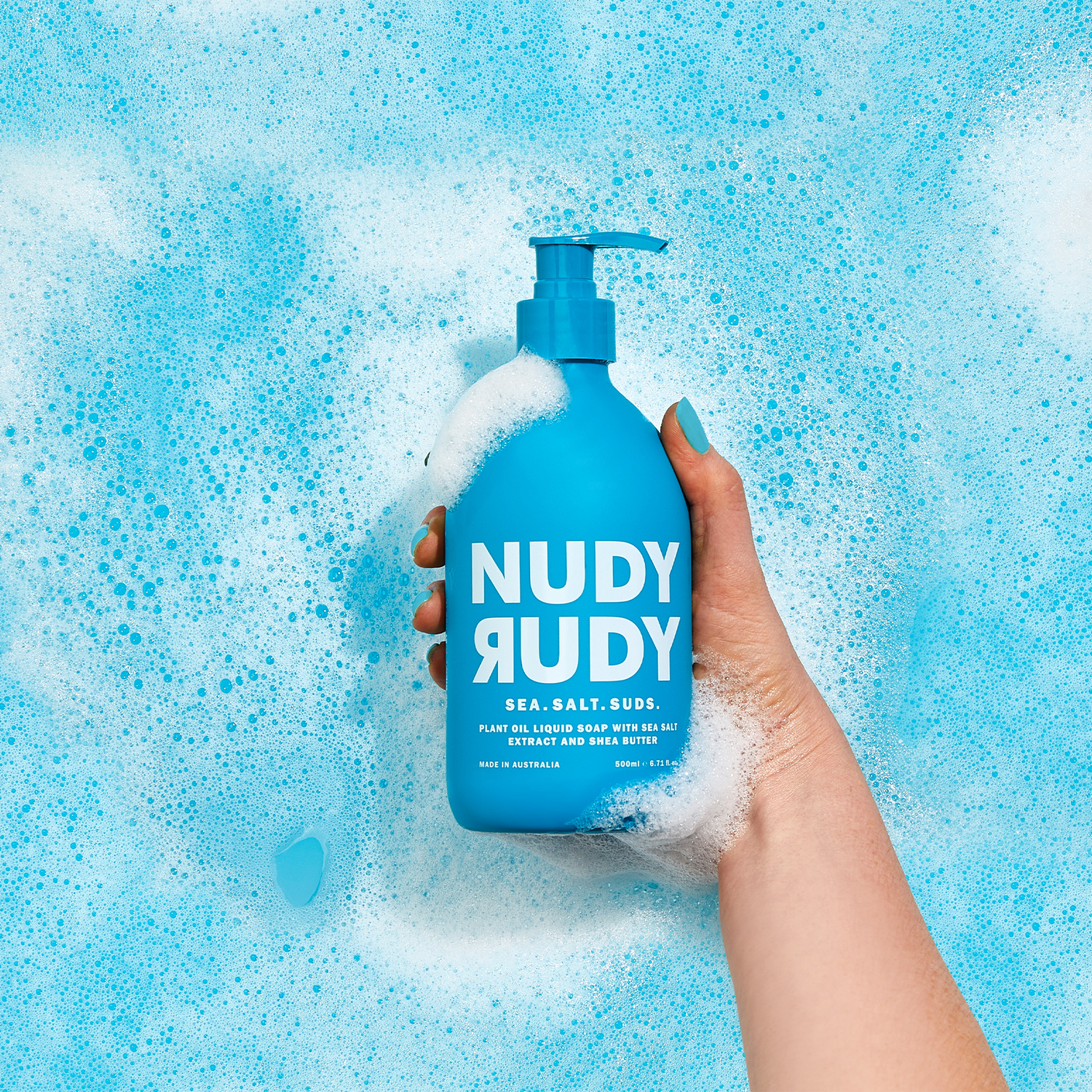 Hand holding a blue Nudy Rudy bottle against a blue bubble background